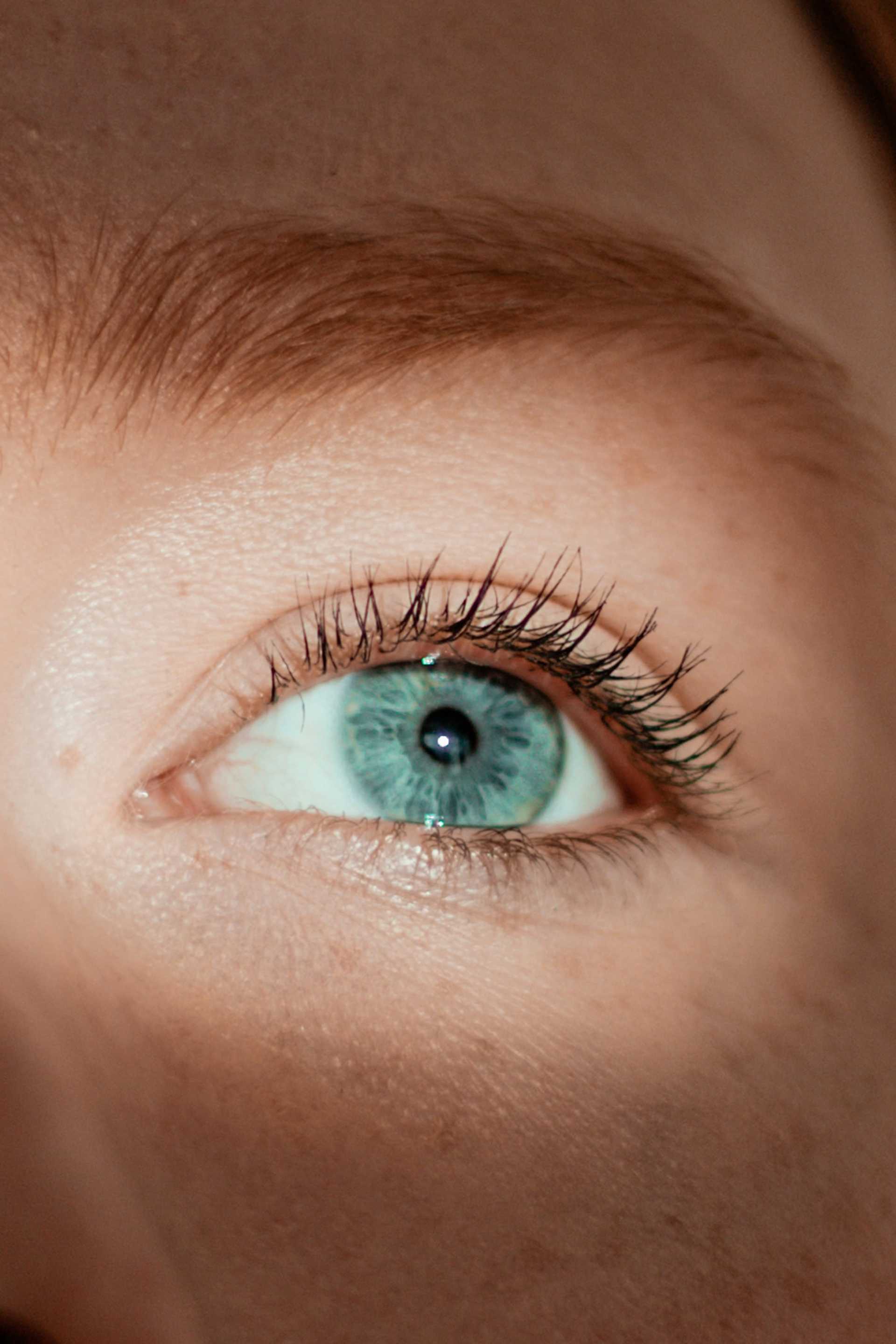 Close-up of a blue eye with natural eyelashes and lighting.